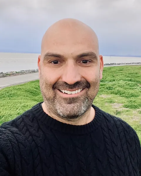 David Dufour, D.C., smiling, outdoors by the San Francisco Bay shoreline