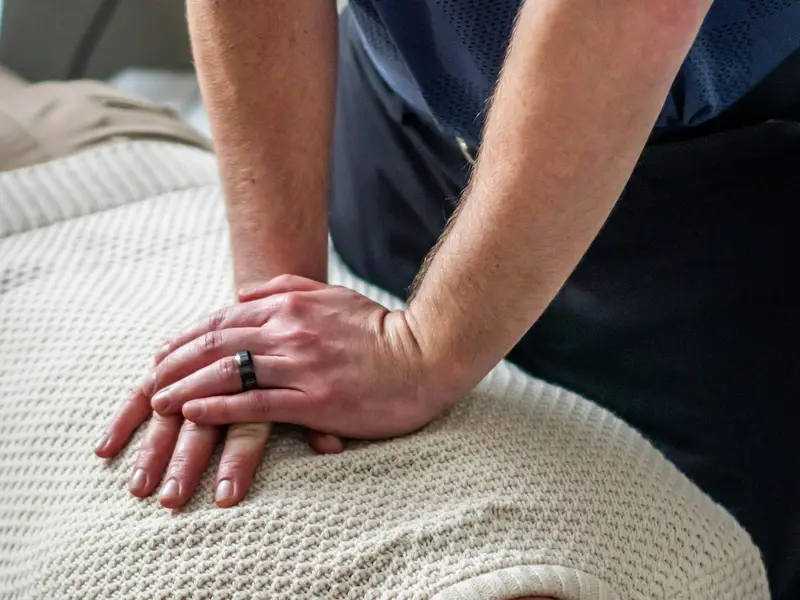 A practitioner's stacked hands applying a chiropractic adjustment to a person's upper back